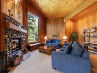 Experience rustic charm in this inviting living room, featuring a magnificent stone fireplace and a soaring wood-paneled ceiling.