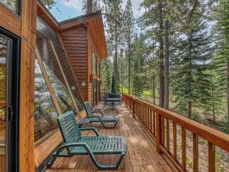Enjoy the serene mountain lifestyle from this charming cabin's expansive wooden deck, perfect for relaxing amidst the towering pine trees.