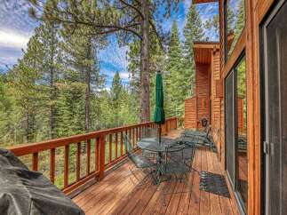 Enjoy the serene mountain lifestyle from this charming cabin's expansive wooden deck, perfect for outdoor dining or simply soaking in the breathtaking forest views.