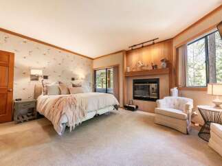 Experience ultimate comfort in this luxurious bedroom, featuring a cozy fireplace and a plush king-sized bed adorned with decorative pillows and a soft throw.