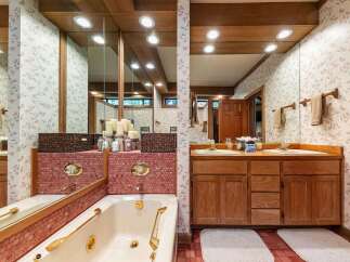 Indulge in relaxation in this charming bathroom featuring a luxurious jetted tub surrounded by elegant pink mosaic tile.
