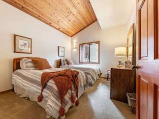 This charming bedroom features two cozy beds with striped bedding and a warm, textured throw blanket.