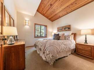 Experience rustic charm in this inviting bedroom, featuring a vaulted wood-paneled ceiling that adds warmth and character.
