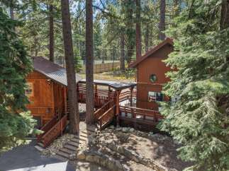 Nestled among tall pine trees, this charming cabin offers a rustic retreat with its warm wood exterior and inviting decks.