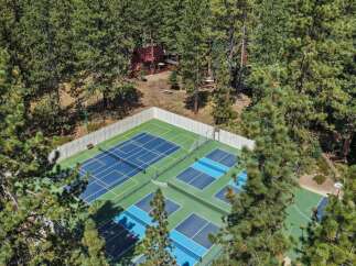 Experience outdoor recreation at its finest with this property featuring multiple sports courts, including pickleball and basketball, nestled amongst mature pine trees.
