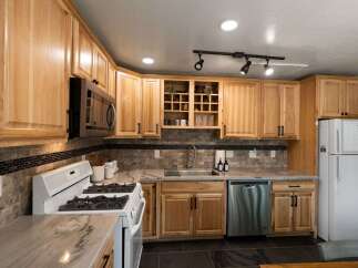 Discover this charming kitchen featuring light wood cabinetry and a sleek tile backsplash.