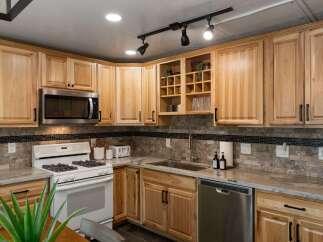 This charming kitchen features light wood cabinetry and a sleek stainless steel microwave.