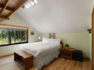 Experience serene living in this charming bedroom featuring a comfortable queen-size bed dressed in crisp white linens.