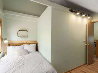 Discover this cozy bedroom featuring a comfortable bed with crisp white linens and plush pillows, perfect for a restful night's sleep.