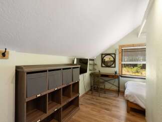 This charming attic room features a functional workspace with a desk and chair, perfect for remote work or study.