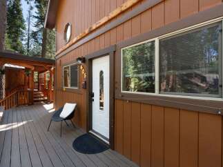 Charming cabin exterior featuring a warm brown wood siding and a welcoming covered porch with wooden railings and stairs.