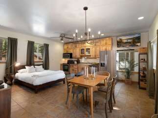 This charming studio apartment offers a comfortable queen-size bed, a fully equipped kitchen with light wood cabinetry, and a dining area perfect for meals.