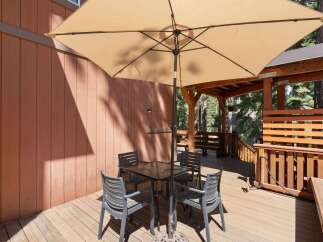 Enjoy outdoor dining and relaxation on this spacious wooden deck, complete with a large umbrella and comfortable seating.