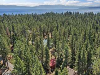 Nestled amidst a dense forest of towering pine trees, this property offers a serene retreat with breathtaking views of a vast blue lake and distant mountains.