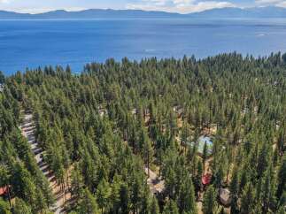 Experience the ultimate lakeside retreat with this stunning aerial view of a property nestled amidst a dense pine forest.