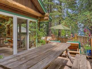 Enjoy outdoor living at this charming log cabin retreat, featuring a spacious wooden deck perfect for entertaining.