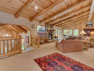 Experience rustic charm in this spacious living area, featuring a stunning stone fireplace and vaulted wood-beamed ceilings.