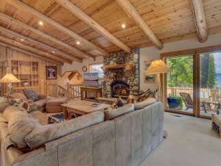 Experience rustic charm in this spacious living room featuring a magnificent stone fireplace and exposed log beam ceiling.