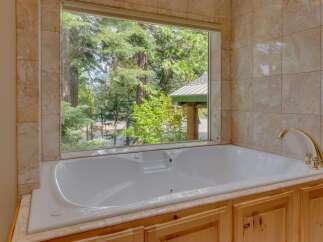 Indulge in relaxation with this luxurious jetted bathtub, offering a serene escape with stunning views of the surrounding forest.