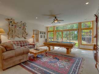 Experience ultimate relaxation in this game room, featuring a rustic log pool table and a cozy plaid sofa.