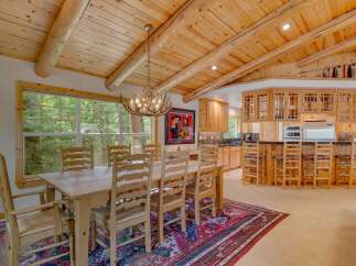 Experience rustic charm in this spacious dining area, featuring a large wooden table with seating for six, illuminated by a unique antler chandelier.