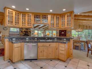 This spacious kitchen boasts custom knotty pine cabinetry with glass-front upper cabinets, perfect for displaying your finest dishware.