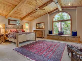 Experience rustic charm in this inviting bedroom, featuring a sturdy wooden bed and a cozy seating area by a large arched window.