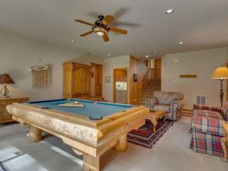 This rustic living area is perfect for entertaining, featuring a custom log-style pool table as the centerpiece.