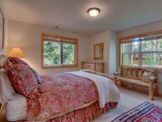 Experience rustic charm in this cozy bedroom featuring a beautiful log-frame bed adorned with a vibrant paisley comforter.