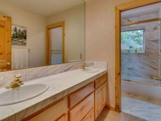 This charming bathroom features a double vanity with marble countertops and elegant brass fixtures, perfect for a shared space.