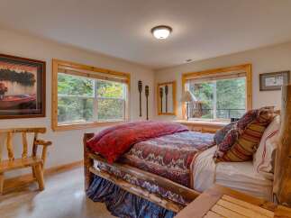 Experience rustic charm in this inviting bedroom, featuring a cozy log bed adorned with a vibrant paisley comforter and plush pillows.
