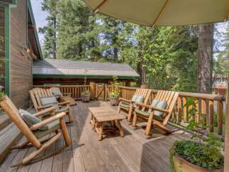 Enjoy the serene mountain setting from this charming wooden deck, complete with comfortable rocking chairs and a rustic coffee table.