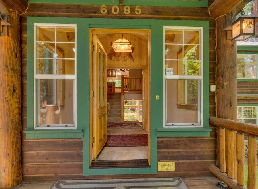 Step into this charming log cabin home, featuring a welcoming open entryway with natural wood accents and a rustic bear-themed chandelier.