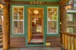 Step into this charming log cabin home, featuring a welcoming open entryway with natural wood accents and a rustic bear-themed chandelier.