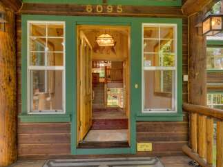 Step into this charming log cabin home, featuring a welcoming open entryway with natural wood accents and a rustic bear-themed chandelier.