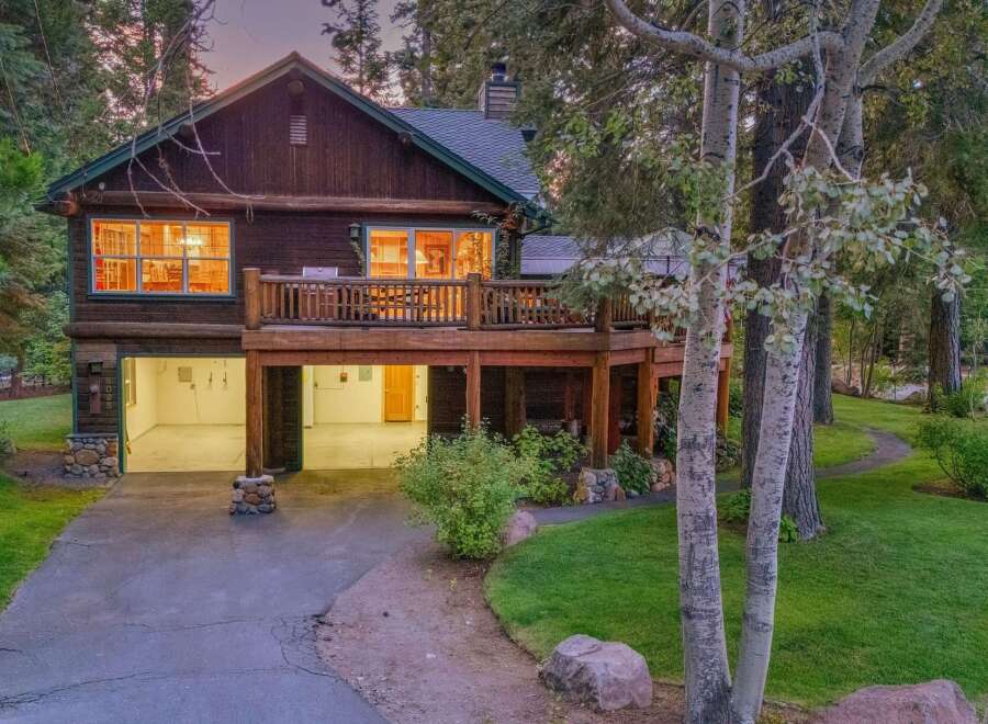 Nestled amidst tall trees, this charming log home offers a serene retreat with its spacious wooden deck and inviting interior.