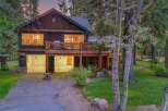 Nestled amidst tall trees, this charming log home offers a serene retreat with its spacious wooden deck and inviting interior.