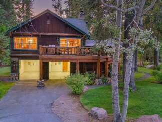 Nestled amidst tall trees, this charming log home offers a serene retreat with its spacious wooden deck and inviting interior.