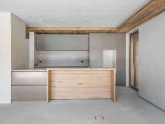 Discover a modern kitchen under construction, featuring sleek grey cabinetry and a natural wood island.