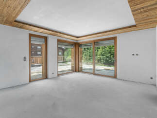 Experience modern living in this unfinished interior space, featuring expansive sliding glass doors that invite abundant natural light and offer picturesque views of the surrounding greenery.