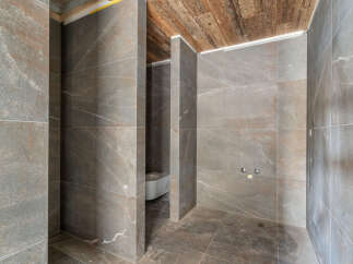 Experience modern luxury in this unfinished bathroom, featuring elegant large-format stone tiles on the walls and floor.
