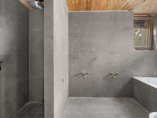 Experience modern luxury in this unfinished bathroom, featuring sleek grey stone tiles throughout the shower and bathing area.