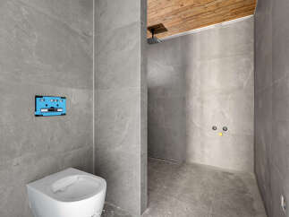This modern bathroom features a sleek toilet and a unique cassette tape-inspired flush plate, adding a playful touch to the minimalist design.