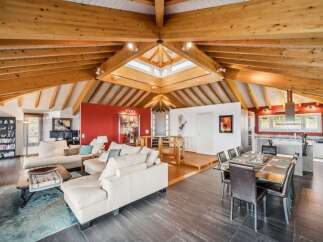 Experience luxurious living in this stunning open-concept home, featuring a vaulted wood-beamed ceiling and a central skylight that floods the space with natural light.