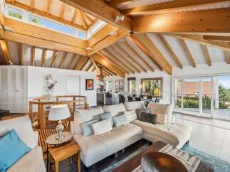 Experience breathtaking views from this stunning living room, featuring a vaulted wood-beamed ceiling and expansive skylights that flood the space with natural light.