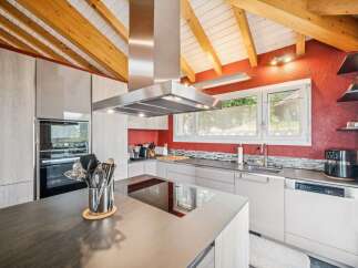 Experience modern living in this stunning kitchen featuring sleek, light wood cabinetry and a striking red accent wall.