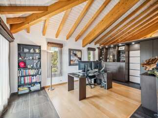 Discover this stunning home office featuring a vaulted ceiling with exposed wooden beams, creating an airy and rustic ambiance.