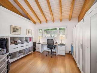 Discover this charming room featuring a spacious white shelving unit perfect for storage and display, complemented by a functional desk area with two side cabinets and a comfortable office chair.