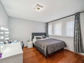 This inviting bedroom features a plush grey upholstered bed with a tufted headboard, complemented by a matching quilted bedspread and two pillows.