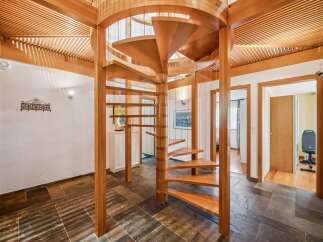 Ascend to new heights in this stunning home featuring a magnificent wooden spiral staircase as the centerpiece of the entryway.
